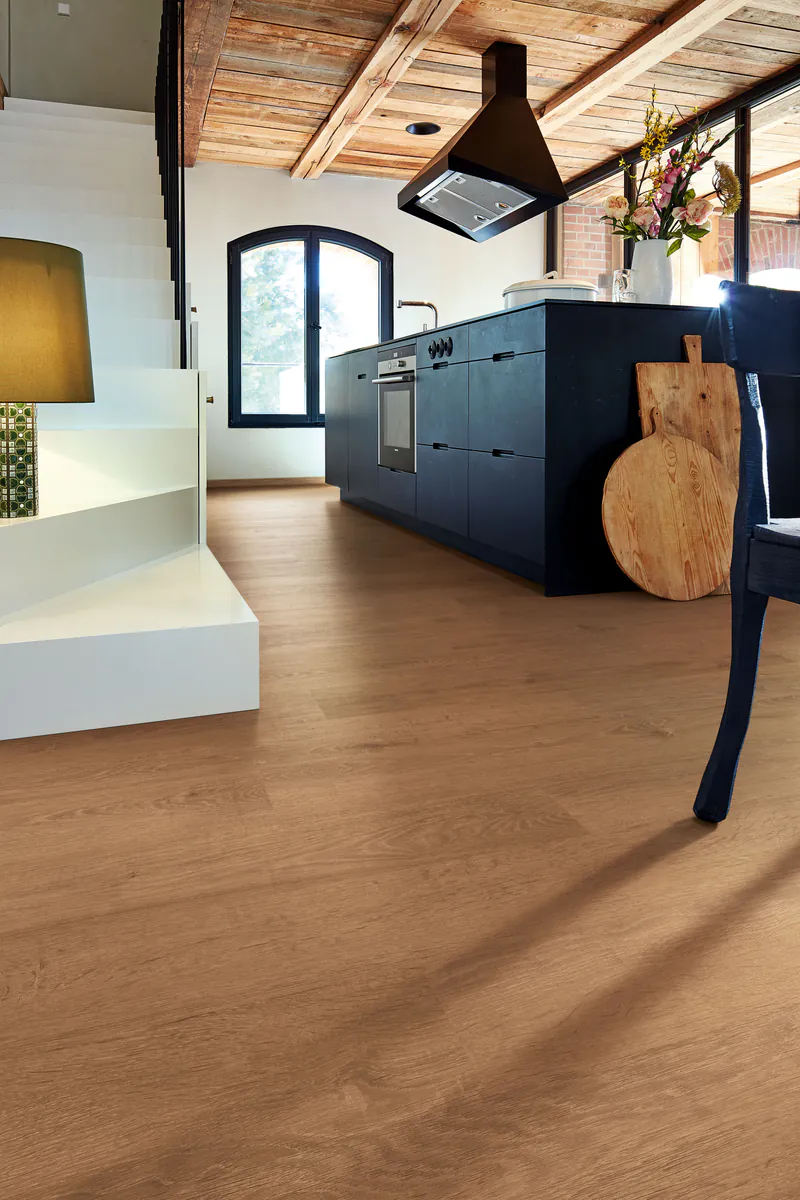 Moderner Wohnraum mit hochwertigem Eichen-Laminatboden in einer offenen Küche mit dunkler Küchenzeile und rustikaler Holzdecke.